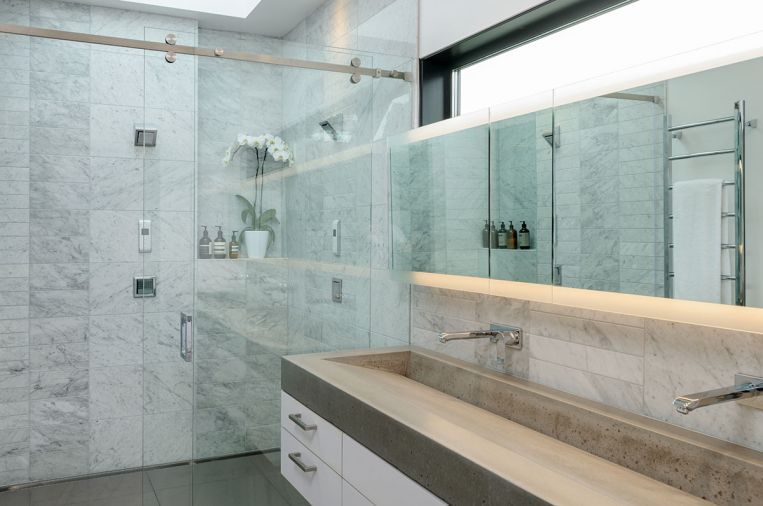 The master bathroom shower is lined in Carrera marble and tiled with porcelain. The sink is a single piece of cast concrete.