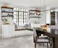 The family’s dining area got cozier with the addition of a window seat centered beneath a steel window and flanked by a pair of built-in white cabinets crowned with a pair of triple-bracketed shelves in a space once occupied by an oversized refrigerator. Adjustable Holtkötter lighting over table.