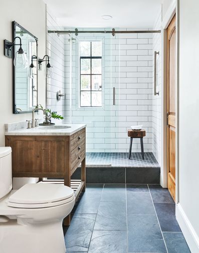 Simplicity is the cornerstone of the powder bath’s design. Olympia 4'x16' white subway tile adds unexpected size and dimension to the shower grounded by black mosaic tile flooring. Fleurco sliding door hardware ties to original steel window protected by a tempered window insert. Slate Ann Sacks flooring; vanity by Restoration Hardware.