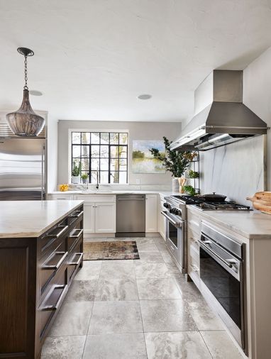 Custom Vent-A-Hood range hood crowns Wolf cooktop. Rohl sink and water faucet. Single Danby marble slab island countertops fabricated by de la tierra, inc. Cabinets are outfitted with drawer pulls from Chown Hardware.