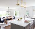 DINING A live-edge dining table and benches are paired with navy chairs, gold accessories, and a black-and-crystal chandelier, complementing the metallic threads in the room’s West Elm area rug.  SINK + HARDWARE A matte silver faucet lends a traditional element to the rectangle-shaped sink from Kohler, while a trio of globe pendants done in gold from West Elm are suspended above.