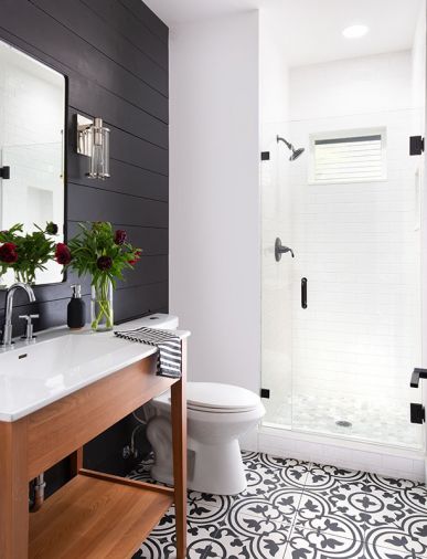 The guest bath features an eye catching black-and-white, large-format porcelain tile from Statements Tile along with a more casual, black-painted shiplap wall and freestanding shower.