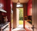 The galley-style kitchen features vibrant red cabinetry with pulls from Cabinetry Northwest, and sleek stainless steel appliances.