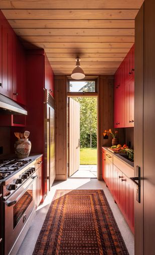 The galley-style kitchen features vibrant red cabinetry with pulls from Cabinetry Northwest, and sleek stainless steel appliances.
