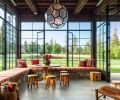 The sunroom is marked by a large, hexagonal-shaped hanging pendant custom designed by Kerry Joyce that is an unexpected contrast to the other, more rustic elements in the space. Steel-framed casement doors can open to let in fresh air, and an inglenook, or partially enclosed fireplace creates a sense of coziness. The sunroom’s meadow views are enhanced by pops of color in cushions with fabric from Romo and Great Outdoors, and fabricated by Washington company Island Custom Upholstery. Pendleton throw blankets and a classic table and stools by Tirto Furniture are a natural fit for the outdoorsy space, along with folding chairs from locally based Terris Draheim.