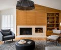 The living room is anchored by a new wood-wrapped fireplace wall with built-in shelving to display the family’s collected items. To “ground the bright, voluminous space and lower the seating area to a cozier human scale,” explains designer Allison Larsen, she added a black Solis Drum pendant light from Pablo that mirrors the round ottoman below.