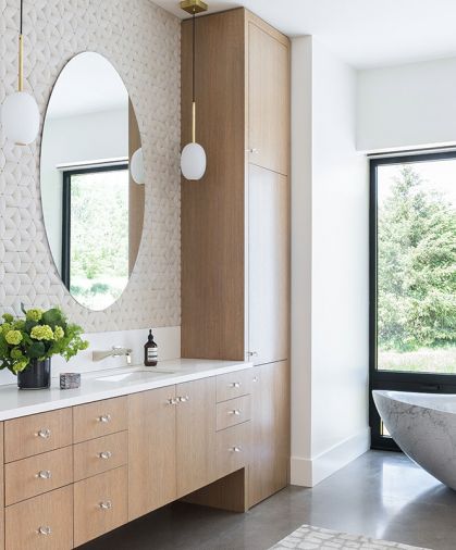 Master Bath dual vanity lit by Atelier de Troupe pendants. Oval mirrors pop against Island Stone “Profiles” “cladding” wall tile. Vanity countertops feature Lapitec matte finish Polare Satin, a sintered stone slab impervious to weather and resistant to stains.