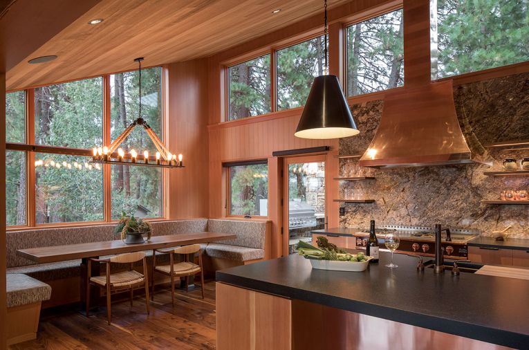 A newly added dining nook in the kitchen offers a less formal area for eating and activities. Designed to be durable, Carolyn Woofer employed Knoll commercial fabric as part of a “refined rustic” look. Pendants over the kitchen island subtly reference cowbells, while copper accents add shimmer against stone.