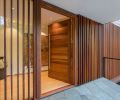 Handcrafted mahogany entry door flanked by mahogany spaced-board screen over a fixed glass pane.