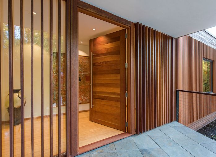 Handcrafted mahogany entry door flanked by mahogany spaced-board screen over a fixed glass pane.