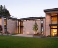 Amber Rose flame stone clad exterior is cut and stacked into three varied sizes to show texture and complex color range. Clerestory windows wrap the home for light yet ensure privacy from street. The Scot Eckley, Inc. landscape design features a gingko tree in a crushed gravel court at right; red Japanese maple left. Photo © Rob Perry