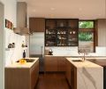 Upper black kitchen cabinet ties visually to the blackened steel entry piece and fireplace and recurs in the island’s footing. Waterfall marble island top countered by a Wolf Cooktop, Vent-a-Hood and repeating marble backsplash. Miele refrigerator is framed by kitchen cabinetry by Warner Cabinets. Photo © Rob Perry