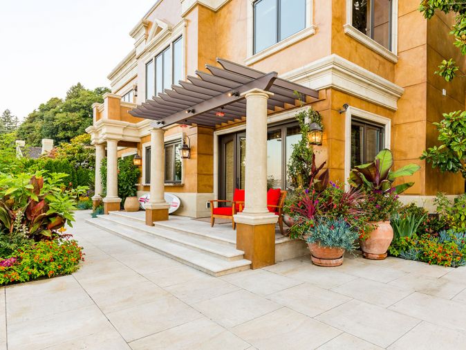 The French limestone terrace acts as a wonderful foil for the joyful color display. Accenting the limestone and architecture, fine Italian Impruneta terra cotta containers are placed throughout the landscape.