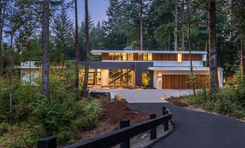 Sited on a 1.2 acre, heavily forested property, this home in the Portland area feels enveloped by the landscape. The exterior blends traditional stucco in two different shades as well as vertical red cedar. Wide overhangs protect the siding while also creating strong horizontal lines in contrast to the vertical cedar. A reflecting pool near the front entrance pulls in light and sets a spa-like tone even before you step inside.