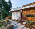 The outdoor walkway that connects the patio to the master bedroom. The exterior is clad in traditional stucco and tongue-and-groove vertical cedar siding.