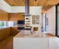 The kitchen ceiling using the same red cedar used for the exterior soffits creates a sense of continuity between indoors and outdoors. “We didn’t want to just have a lot of white surfaces, but we also didn’t want all wood surfaces, so this was a blend of bringing that warmth into the house without having it take over,” says Tim. The kitchen cabinetry and floors are white oak, while the wrap-around cabinetry in the entryway is walnut. The sleek kitchen is fitted with a Miele dishwasher, Miele oven, Wolf Cooktop, and a Sub-Zero refrigerator.