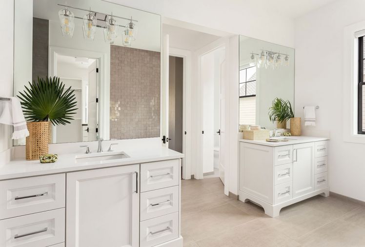 The master bathroom echoes the lovely light feeling in the rest of the house. Hayes Cabinets provided the cabinetry, which pair with white countertops, chrome hardware, and lighting fixtures. A concrete-look porcelain tile on the floor and raised geometric tile accent wall behind the freestanding bath round out the space, while large mirrors reflect the room’s coveted light.