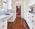 Original butler’s pantry glass cabinetry and cup bin pulls left. Jeff’s hidden VRV HVAC panel design is held up with earth magnets. Currant red dining room walls and oversized poster art seen beyond.