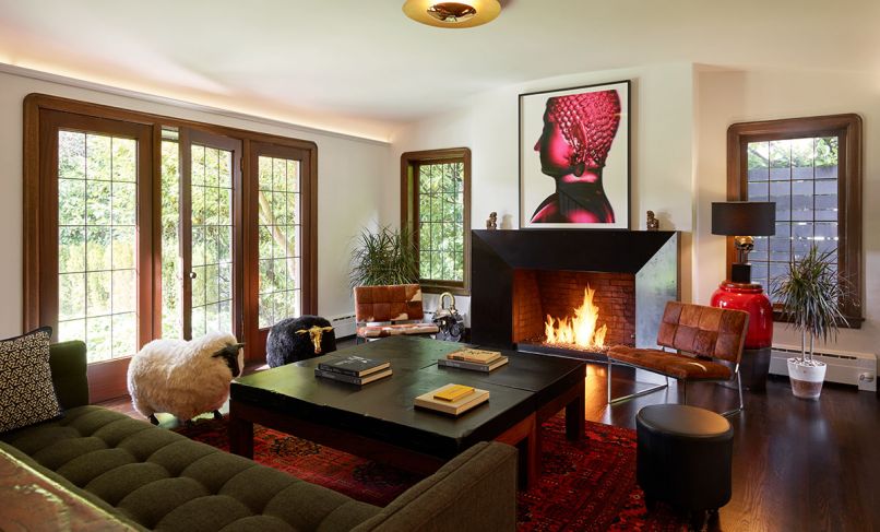 Key architectural elements of this 1927 Tudor style home with French Normandy flourishes remain intact today: voluptuously curved mahogany windows, trim and leaded glass windows restored to their former glory. In the living room, Chadbourne + Doss Architects brought the existing fireplace front and center with a faceted blackened steel surround. Gleaming Blaze lighting by Modern Forms draws the eye to new cove uplighting. Homeowners’ artwork, a Buddha photograph, adds drama to historic architecture.