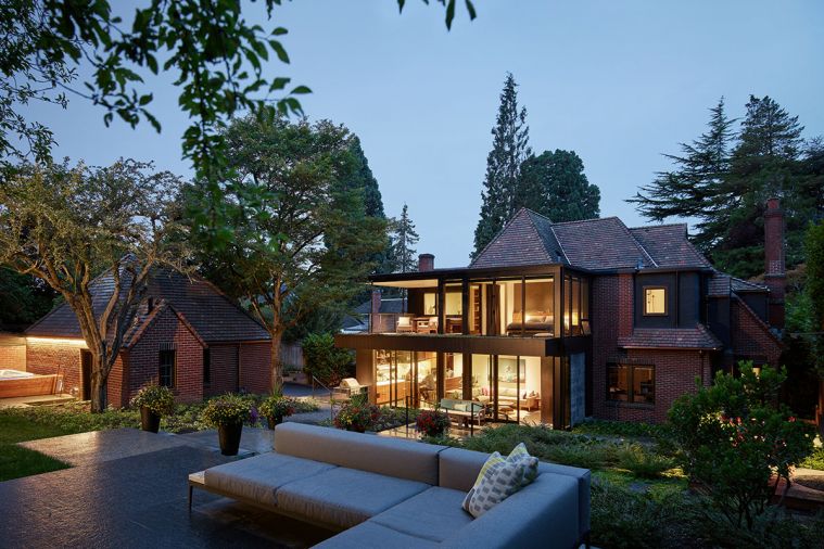 A newly terraced and landscaped backyard features an L-shaped seating area. A bathroom was incorporated into an existing garage with a hot tub behind it. A conservatory-style modern addition includes a new kitchen and family room with hydronic radiant flooring.