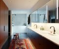 Gone are the maze of separate small masterbath rooms, now the suite is unified by a sleek double-sink walnut vanity, Milestone plaster flooring, walk-in shower, Brizo Odin fixtures, and a custom marble soaking tub.