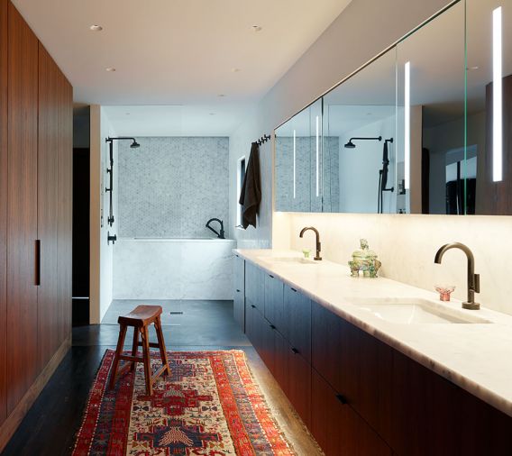 Gone are the maze of separate small masterbath rooms, now the suite is unified by a sleek double-sink walnut vanity, Milestone plaster flooring, walk-in shower, Brizo Odin fixtures, and a custom marble soaking tub.