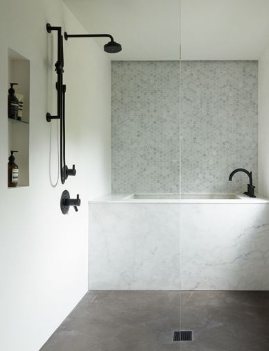 Custom marble soaking tub, Venetian plaster, Hex Carrara accent wall.