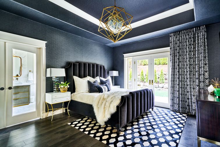 Worlds Away nightstands flank the Bernhardt Interiors bed with custom velvet upholstery trimmed with Art Deco nail heads. Custom drapery fabric by Stacy Garcia Tri-Kes. Visual Comfort Kelly Wearstler chandelier draws eye up toward black painted ceiling. Black wallpaper by MDC Wallcovering adds dramatic texture to the room.