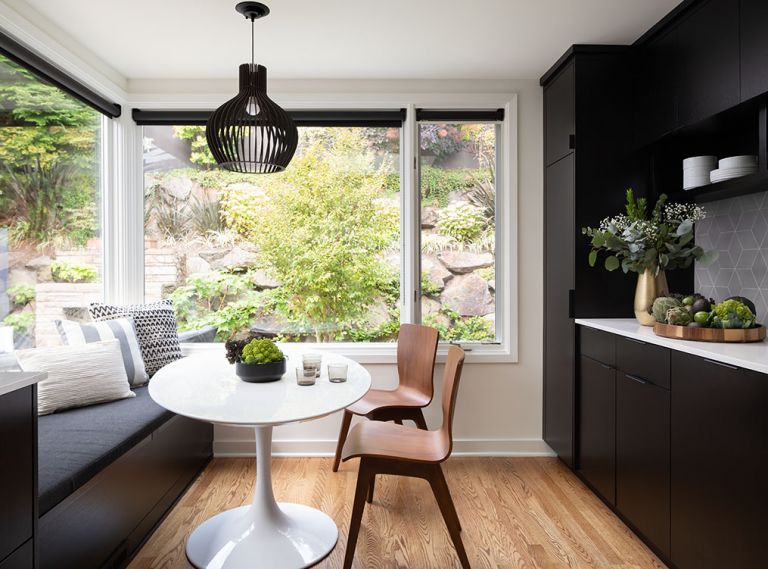 In one portion of the kitchen, designers Alex Childs and Brooke Prince created a dining nook. A built-in bench matches the cabinetry and conceals storage space underneath the cushions. The pedestal table and bentwood dining chairs incorporate touchstones of mid-century modern style.