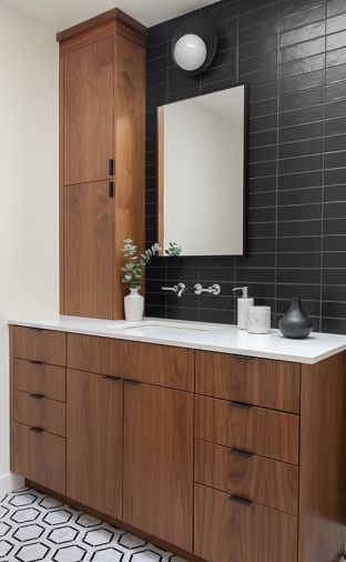 Two different tile patterns in the master bathroom sustain the subtle focus on the pattern established in the kitchen. The team chose two different geometric tile patterns—one for the floor, and a different tile for a full-wall backsplash behind the sink. Chestnut-toned stain on the walnut cabinets bring warmth into the bathroom and help the cooler tones pop.