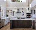 The kitchen and dining room’s airy vibe comes thanks to its two-story space and abundant windows. Kitchen cabinetry is a combination of lighter gray on the perimeter and a darker blue-gray hue for the island cabinets. Soft white honed Carrara marble countertops complements tile that mimics the movement of waves. “This all adds lightness and reduces the weightiness of the home on its occupants,” explains homeowner Selma Pierce.