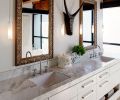 A South African mask purchased during the couple’s travels to that country bisects the master bath’s dual vanity mirrors. Calacatta Caldia slab countertops.