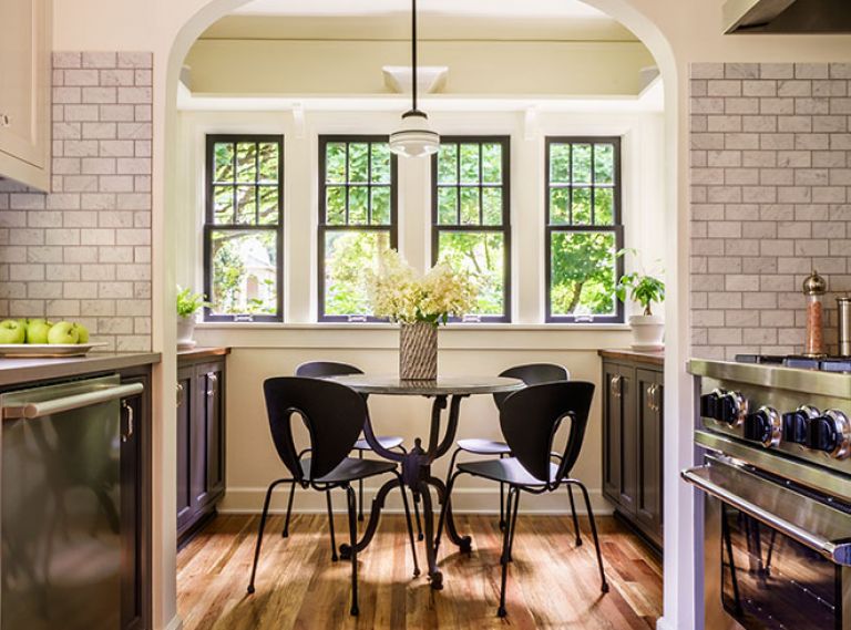 There were two elements of the 1925 cottage kitchen that Chelly knew she would maintain: the arched entry into the breakfast nook and the original windows and glass. Adding display shelves with corbel brackets increased storage space, as did the construction of new cabinetry painted Benjamin Moore Wrought Iron like the kitchen cabinets. Mixing modern with period correct furnishings inspired the combo of comfy Design Within Reach Globus chairs paired with a traditional wrought iron legged table from Rejuvenation.