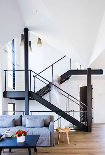 An open steel frame staircase with oak treads echo the home’s wide plank European oak flooring. Large Loewen windows bath the staircase in light along with a trio of Finnish Secto pendants. Artiss’s own slab ceramic box on paired black and white oak Josh Vogel coffee tables.