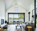 La Cantina sliding doors that overlook WA State Ferry Dock are framed beneath 15  ceiling rising to apex of one of its cross gabled roofs. Embrace Chairs by Carl Hansen/Austrian trio EOOS flank the Crystal White marble fireplace surround. Danish Muuto side tables.