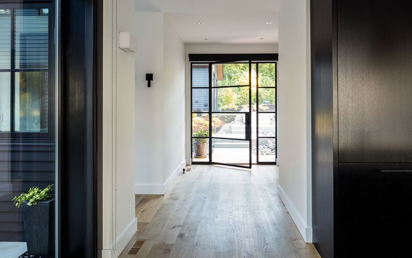 Looking from kitchen toward Portella steel and glass entry door with flanking side lights. Garage visible beyond.