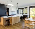 Louis Poulsen pendants add task lighting for rift sawn oak honey stained island with quartz stone countertop. Sub-Zero flat paneled black stained cabinet and recessed pantry. DWR tractor stools. Strand & Hvass Extend Table features modern fold out black leaves.