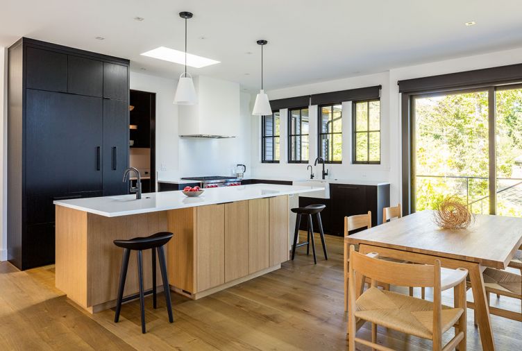 Louis Poulsen pendants add task lighting for rift sawn oak honey stained island with quartz stone countertop. Sub-Zero flat paneled black stained cabinet and recessed pantry. DWR tractor stools. Strand & Hvass Extend Table features modern fold out black leaves.
