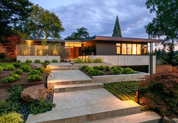 Williams’ architectural design lends new importance to the master by placing it above the garage now tucked out of sight below. Privacy comes from a wraparound concrete balcony. Shapiro Ryan’s wide concrete walkway rises elegantly through the graduated, terraced minimalist landscape, with grass eye-break before Williams’ wood and steel fencing perched atop concrete.