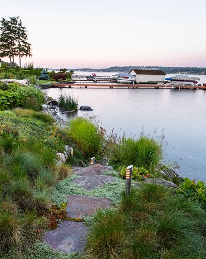 The pathway down to the pebble beach is trimmed with wooly thyme. Hardstem bulrushes protect against wave erosion and stabilize soil. Custom pathway lights by Broadhurst + Associates.