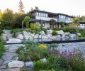 Where only lawn once sloped toward the failing bulkhead, now a black infinity pool backed by boulders and vegetation are at the heart of the family compound.