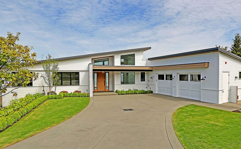 Sturman used 10' Boral tongue and groove painted shiplap planks graduated to 6' planks to break up the façade. Custom white-washed brick entry wing wall. Stained door; Marvin sidelights. Lower level includes children’s bedrooms, art studio, spa, workout room, laundry, and storage.
Photograph © Tucker English