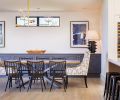 Dining room, adjacent to both kitchen and pantry on one side and living area on other, views covered deck through La Cantina multi-slide glass door. The soffit aligns with roof plane change above. Grids on custom buffet matches pattern on master walk-in closet barn door. A mix of geometric patterns, including Leathercraft host chair fabric, the Four Hands “Spider” crossed table legs and buffet doors, all from J Garner Home. Restoration Hardware chandelier.