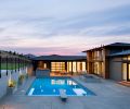 The pool, spa and cabana located on the south-facing side of the home include views of the Peak of Badger Mountain. At right, the master bedroom features direct access to the pool and sports court beyond.