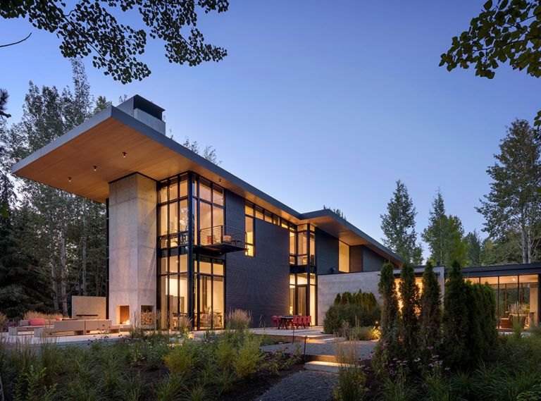 The steel-and-wood-clad Stirrup House features Fleetwood Kona Windows beneath a steel roof system that flexes beneath weighty snow. Glass-box master suite right occupies the secondary portion of “T” shape architecture. 
Photography ©Aaron Leitz