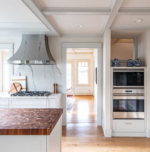 The homeowners requested that appliance spaces were maintained. A pass through to the left of the cooktop gives a glimpse of the rest of the home, while a cutout above the wall ovens provides light to a hallway.