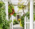 Gated white entrance crowned by soaring columns mark alleyway to both kitchen ahead and formal entry at right.