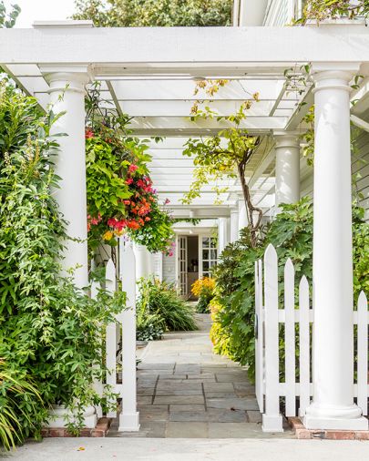 Gated white entrance crowned by soaring columns mark alleyway to both kitchen ahead and formal entry at right.