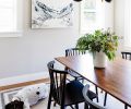 A trio of professional architects, interior designers, and contractors teamed up with homeowners to remodel this 1927 bungalow, by moving the isolated galley kitchen from back of house to front, with Mya Kerner artwork and McGee & Co chandelier adorning dining room alongside enlarged kitchen.