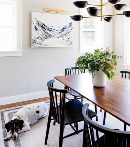 A trio of professional architects, interior designers, and contractors teamed up with homeowners to remodel this 1927 bungalow, by moving the isolated galley kitchen from back of house to front, with Mya Kerner artwork and McGee & Co chandelier adorning dining room alongside enlarged kitchen.
